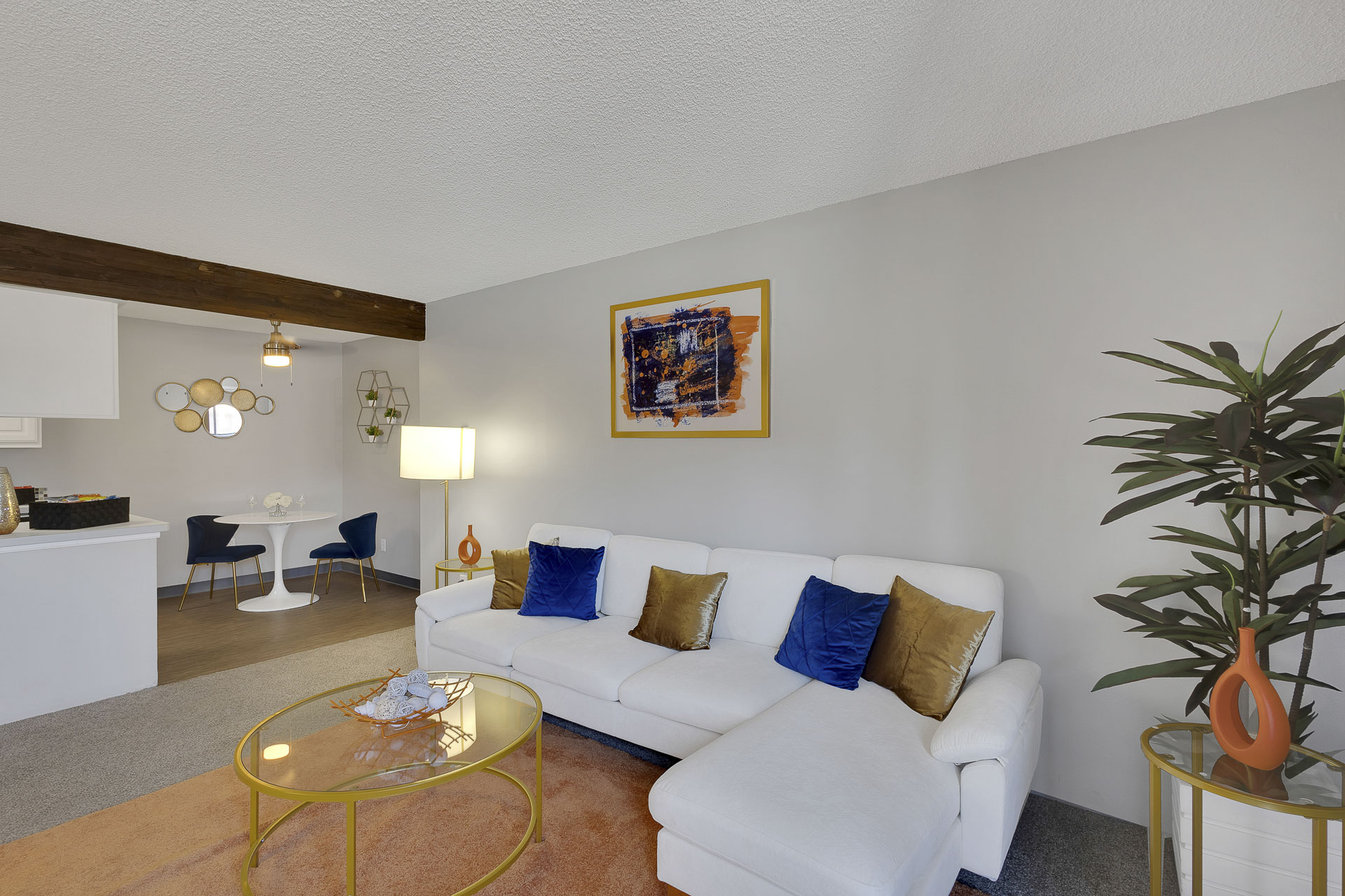 Living room area with sofa, leading into the dining room and kitchen area